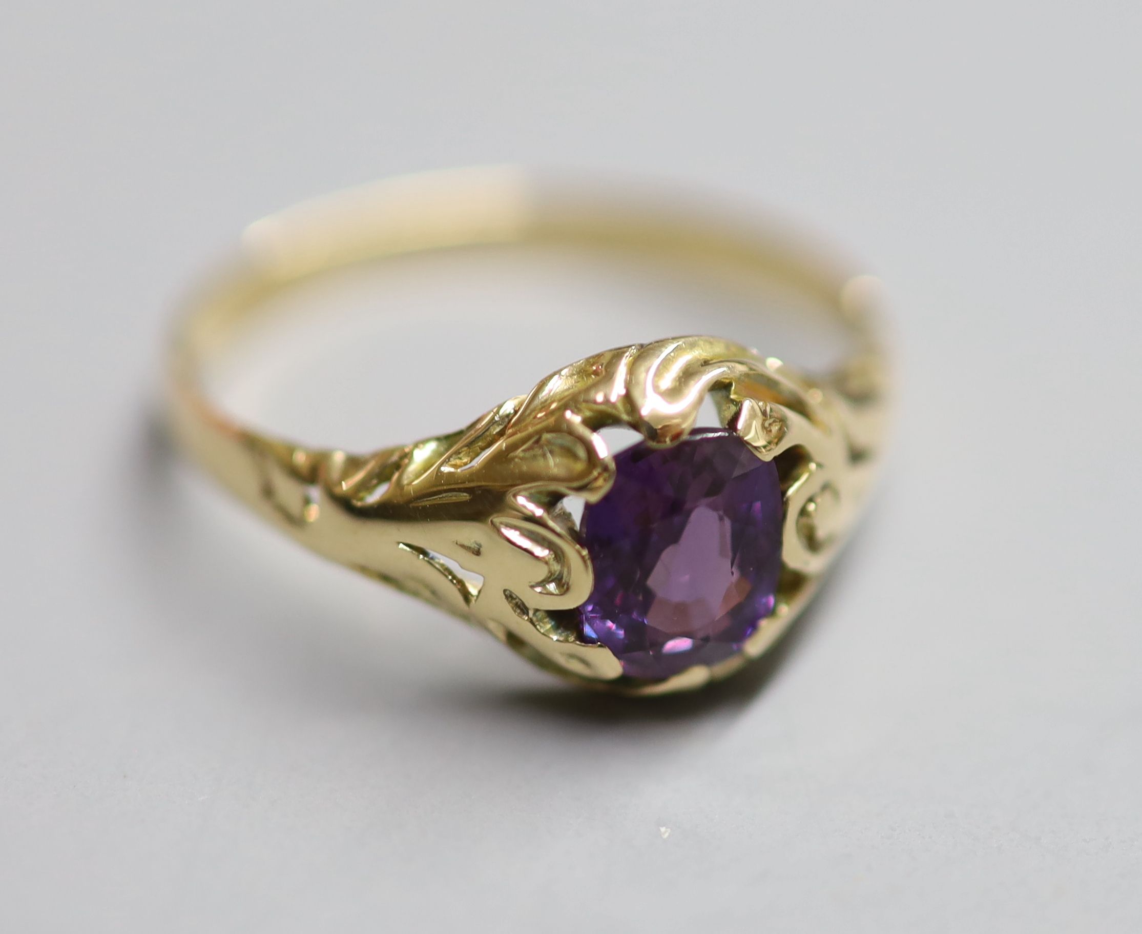 A yellow metal and natural purple sapphire set ring